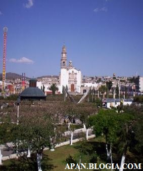 La Iglesia sobresaliendo de las copas de los árboles del Jardín Municipal.